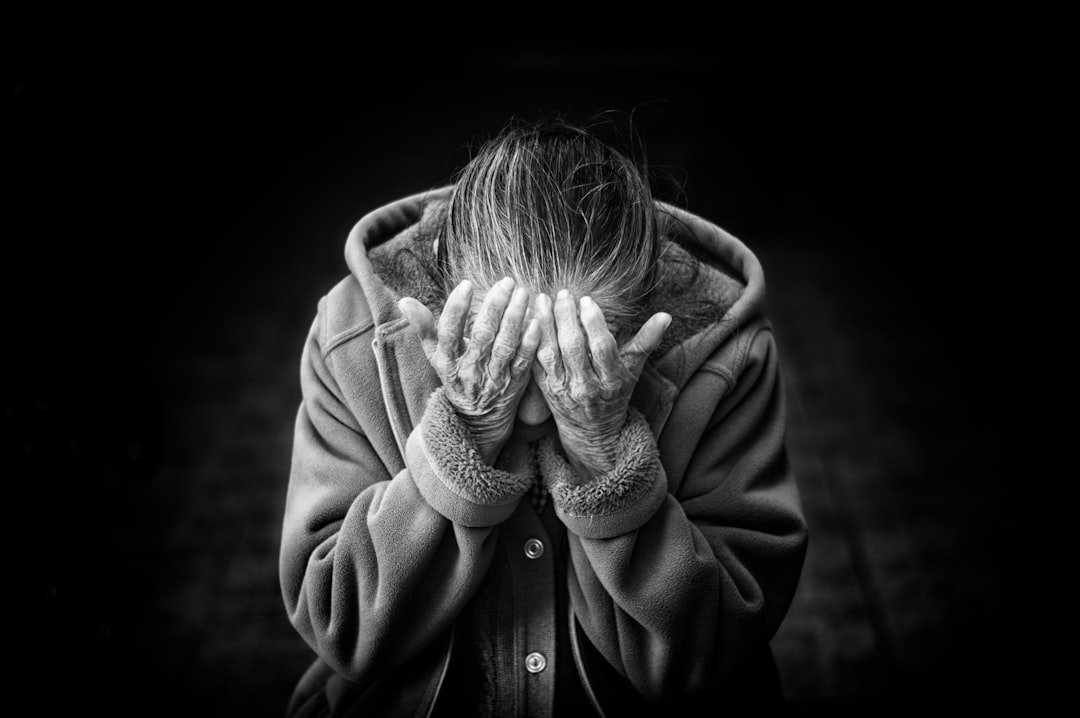 Schwarz-weiß Foto einer Person, die ihr Gesicht - Symboldbild Demenz und Alzheimerverdeckt